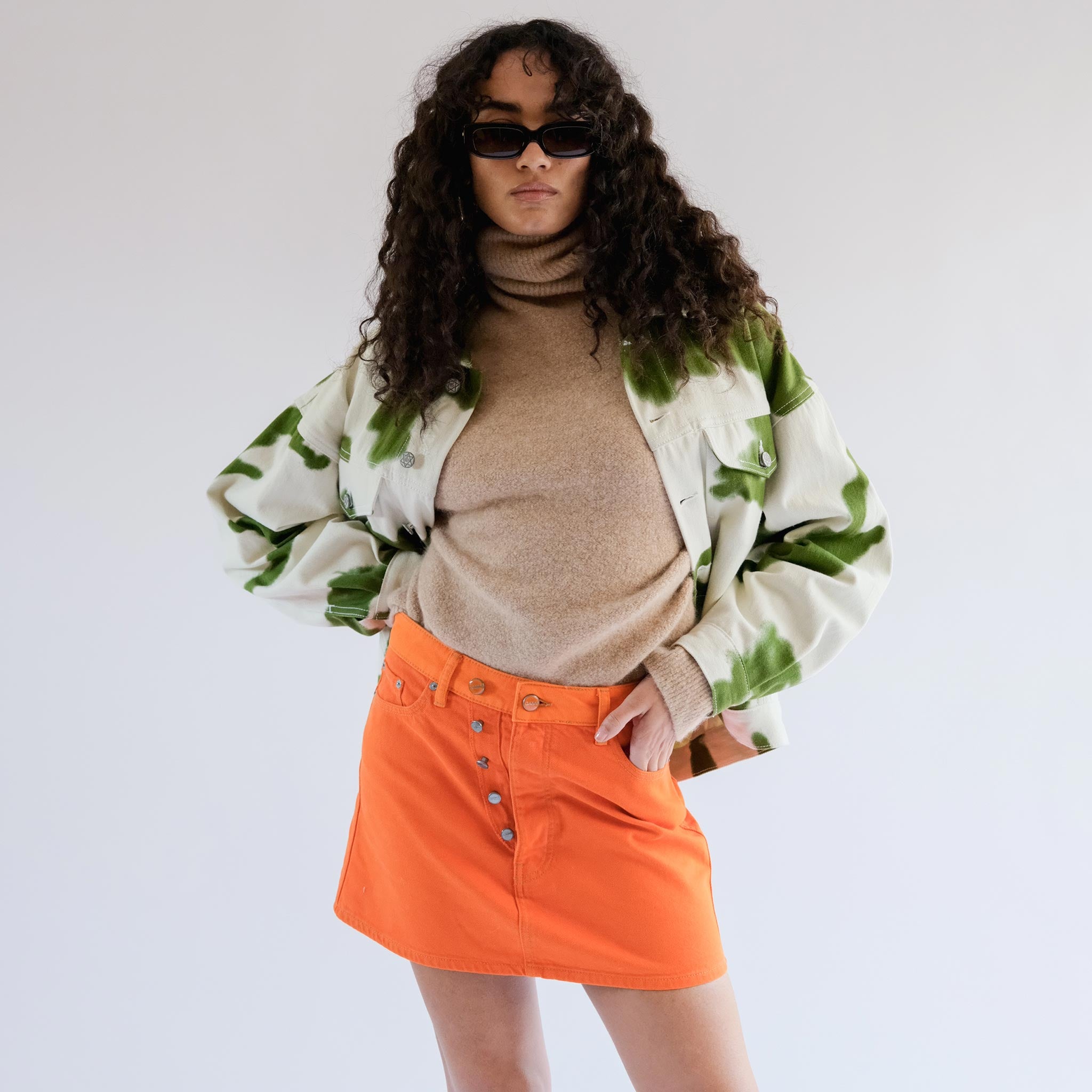 Close half body photo of model wearing the Overdyed Cutline Denim Double Fly Mini Skirt - Orangeade.