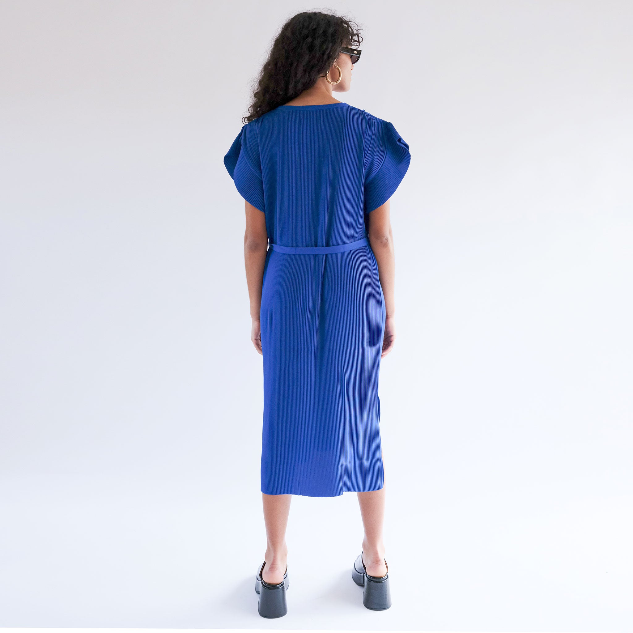 Back full body photo of model wearing the Pina Plissé Dress - Navy.