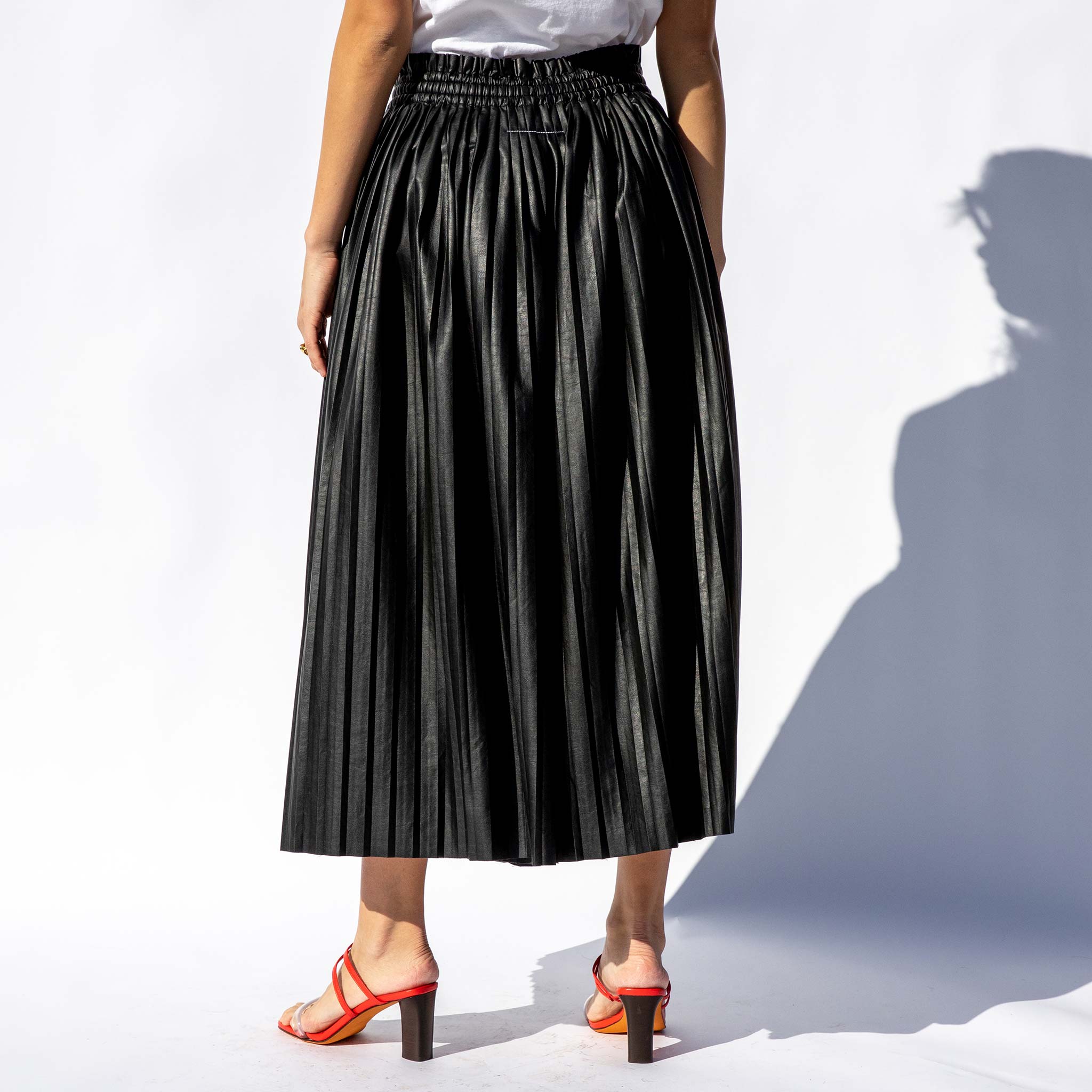 Back half body photo of model wearing the Pleated Skirt / Pants.