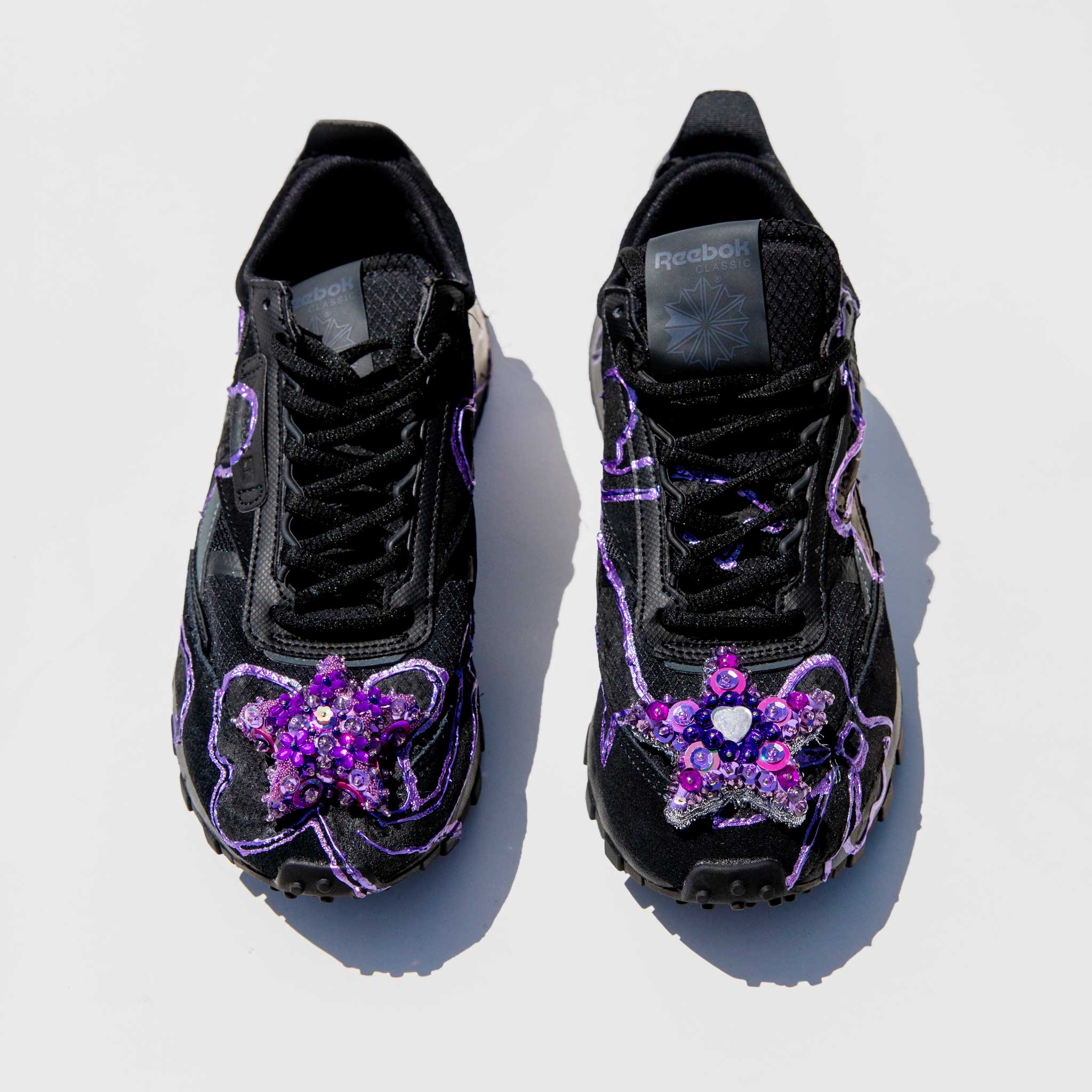 Top straight view of the collina strada reebok sneaker with a purple painted bow detail and a sequin star detail on the toe. 