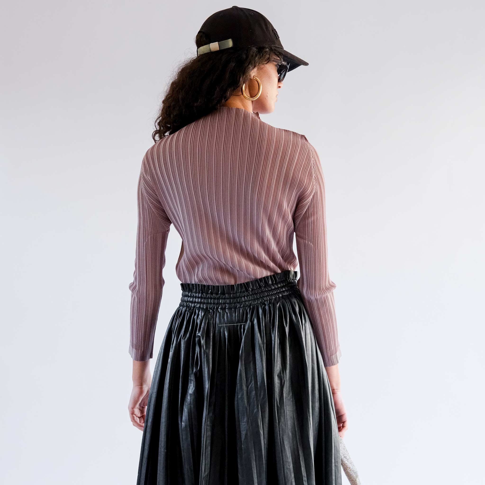 A model wears the mockneck ribbed turtleneck in a light mocha brown - back view.