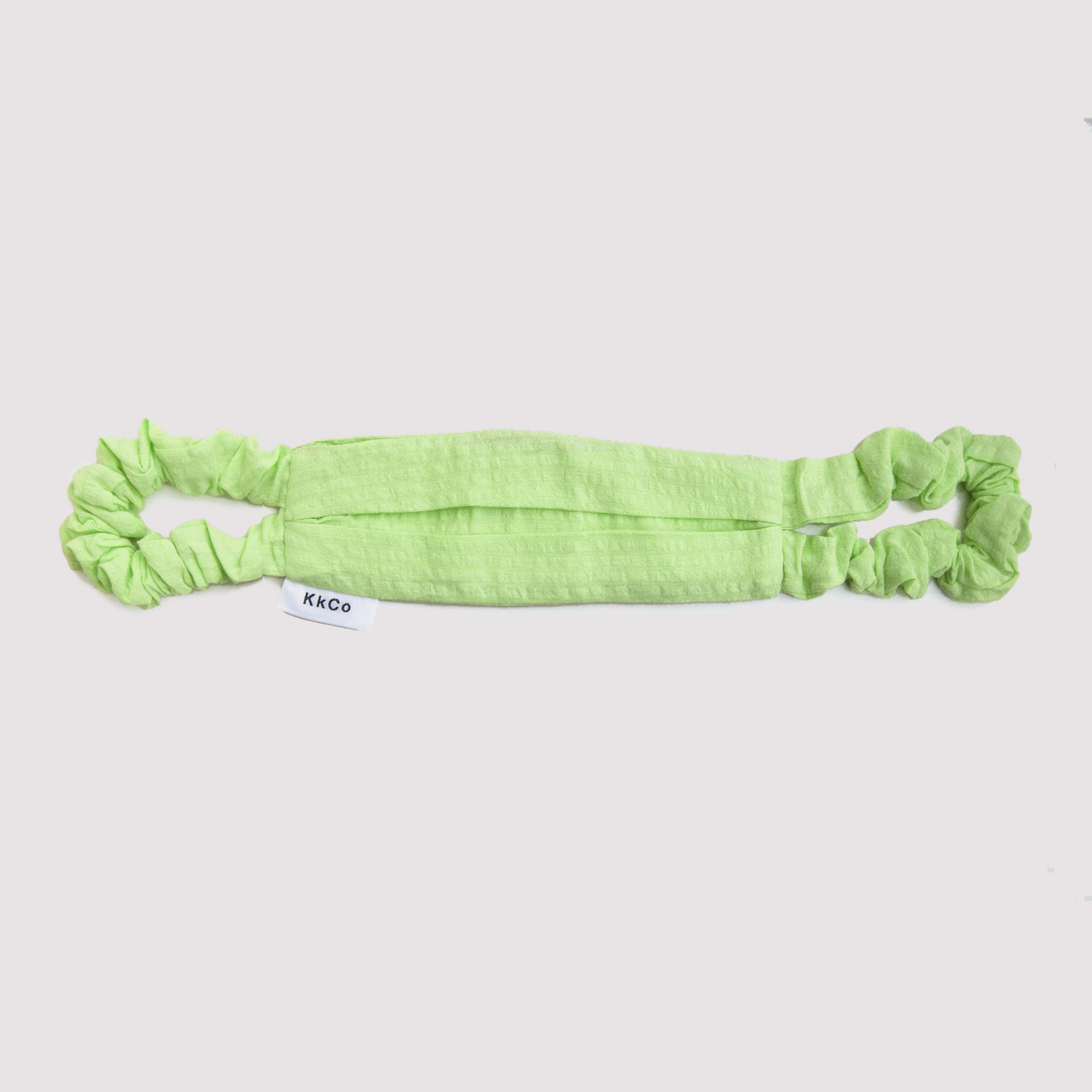 Flat photo of a lime green cloth face covering featured a slightly puckered fabric and scrunchie style ear loops.