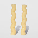 Photo of a pair of natural beeswax candles in a serpentine, crooked wave column shape.