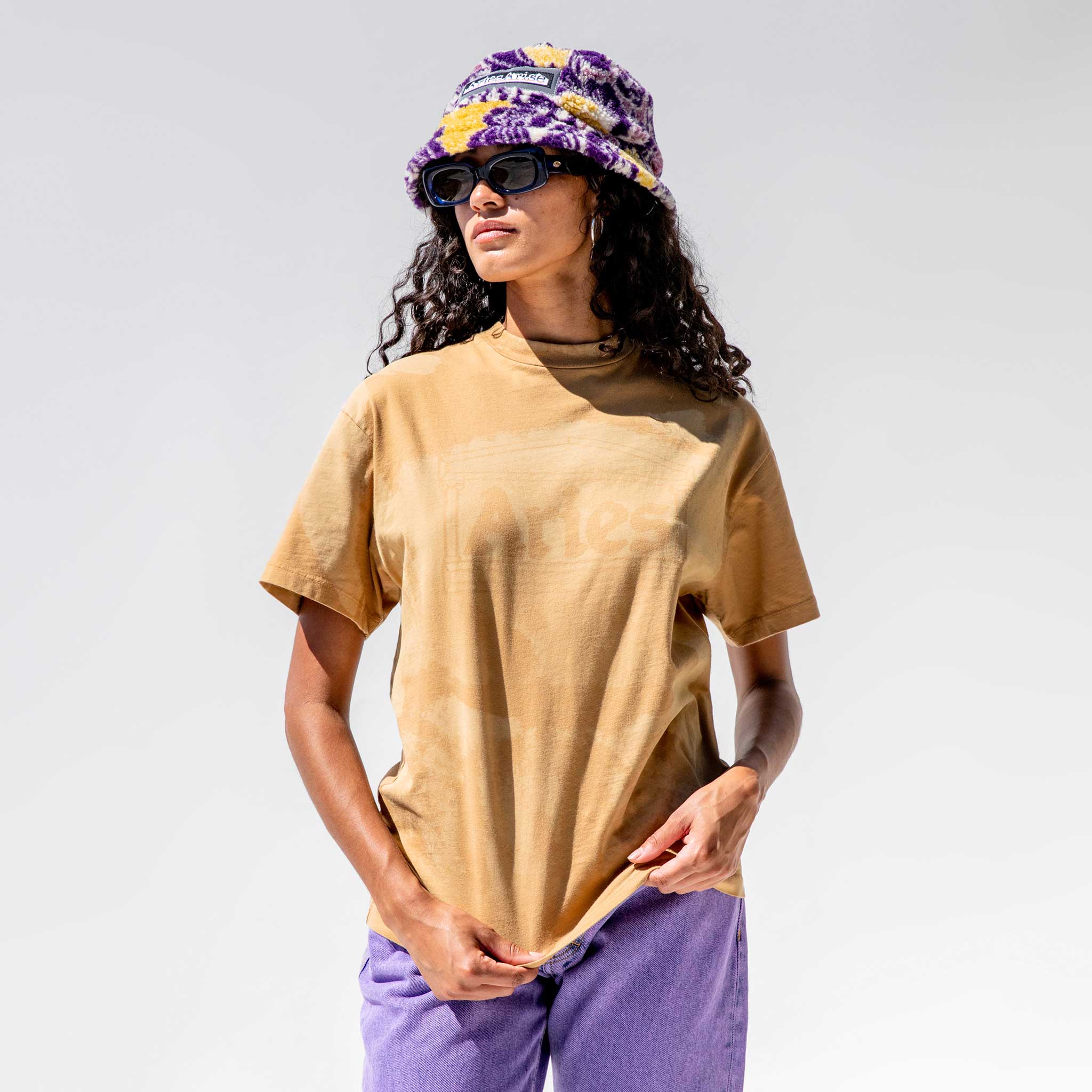 Close half body photo of model wearing the Sunbleached Mega Temple Tee - Camel.