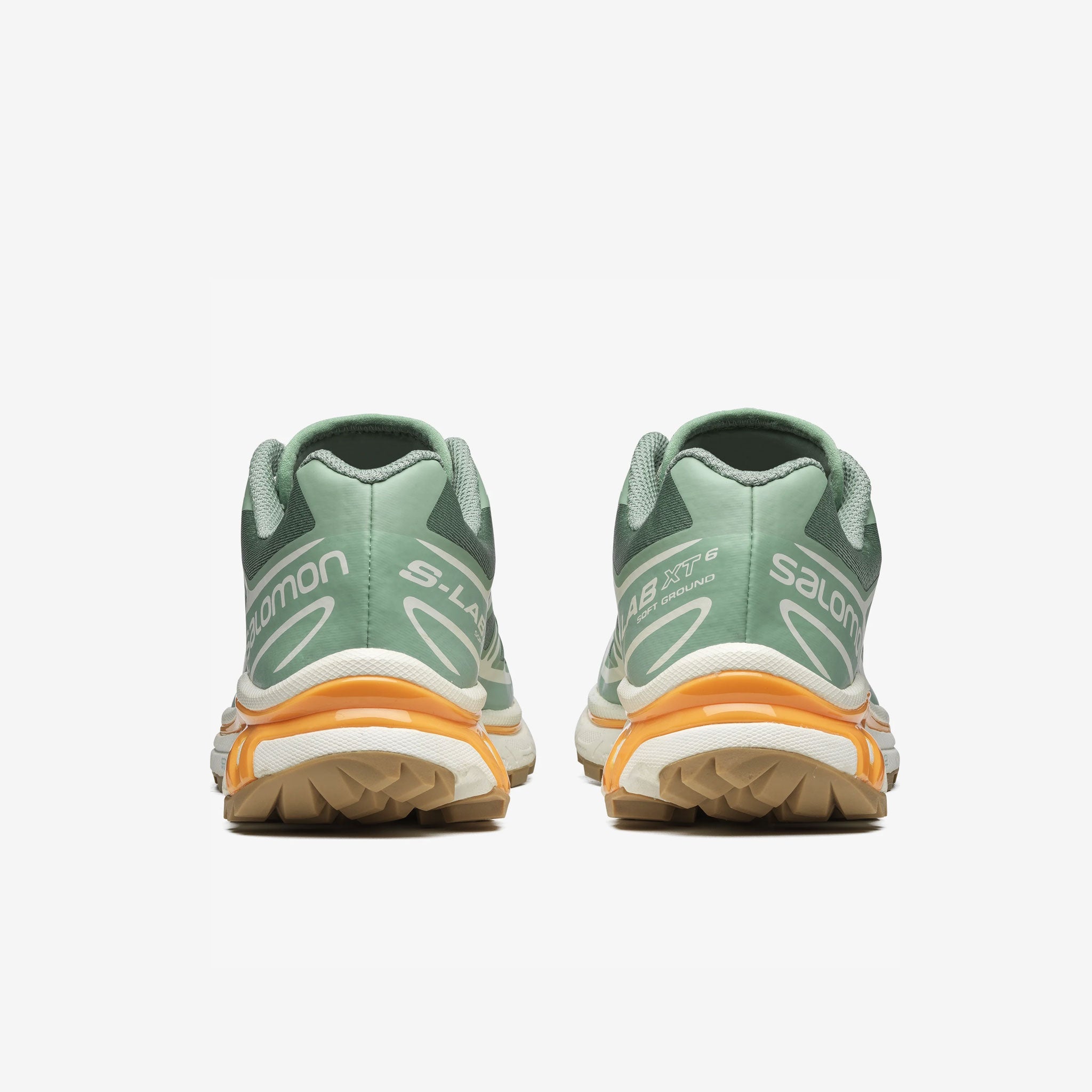Salomon XT-6 sneakers in a pale green colorway with light orange trim along the sole. Back view.