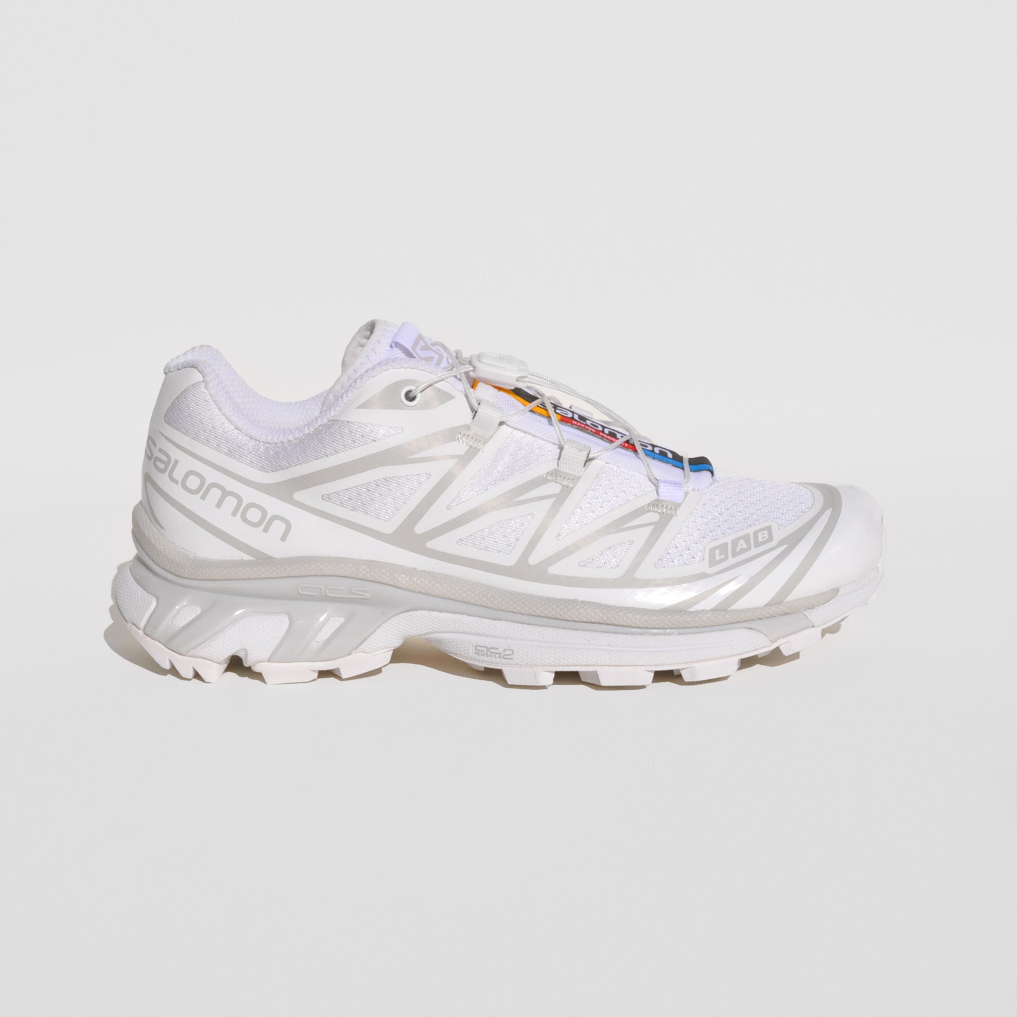 Flat image of the XT-6-white sneakers by Salmon sport style in white. These sneakers are white with their rainbow logo down the middle tongue.